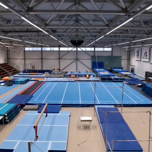 Grote indoor sportzaal met verschillende opgestelde blauwe sportvelden, geschikte voor basketbal en andere groepsactiviteiten.