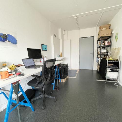 Modern kantoor met witte bureaus, kantoormeubilair, computers en een boekenkast tegen de muur.