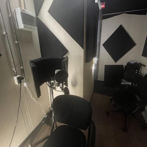 Studio-interieur met akoestische, geometrische wandpanelen en donkere studiobestoeleing.