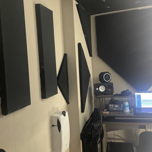 Muurmontage van meerdere zwarte speakers en een audiosysteem in de hoek van een home theater kamer.