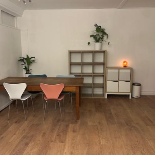 Modern ontvangstruim met een lange tafel, twee stoelen en een boekenplank.