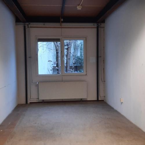 Grote, lege galerij met een lichtgevend raam in het midden van de achterwand.