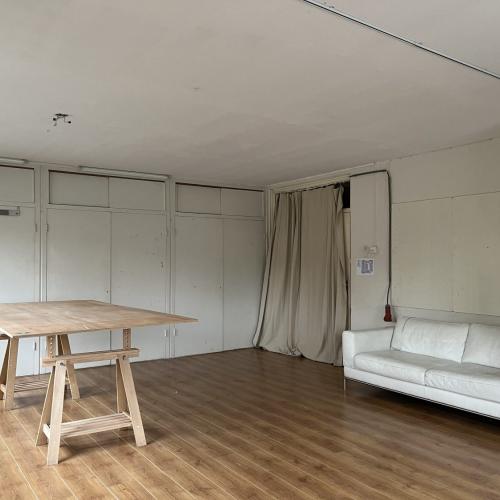 Ruime, lichte interieurfoto met een houten tafel en witte bank in een moderne woonruimte.