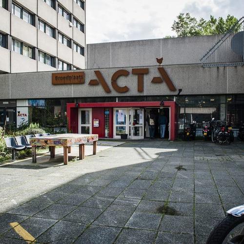 Entreegebied van een grote ACTA supermarkt. Er is een lege parkeerplaats en een motorfiets staat op de voorgrond.