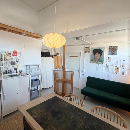 Zicht op een lichte, ruime woonkeuken met een grote eettafel, witte keuken en een donkergroene bank.