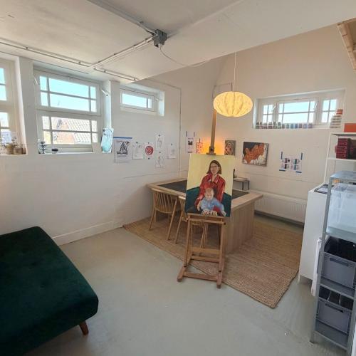 Een zonnige woonkamer met een groene bank, ramen en een speelhoek.