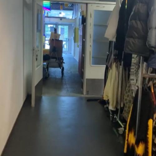 Nauwkeurige afbeelding van een winkelgang met kledingrek aan de rechterkant en een lege, witte gang links.