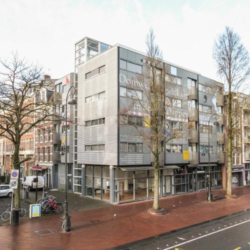 Moderne kantoorgevels naast oude gebouwen, met voor een breed trottoir en parkeerplaats.