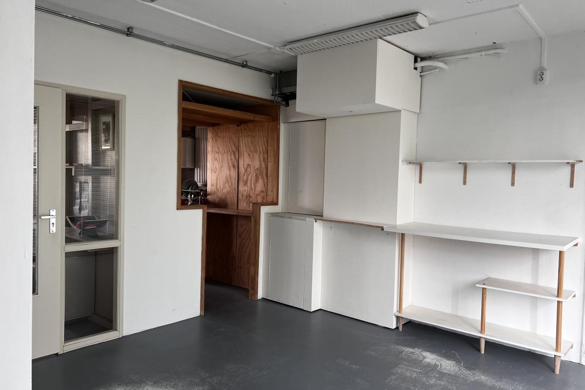Modern interieur met witte ingebouwde kasten, een houten nis en open, minimalistische planken aan de muur.