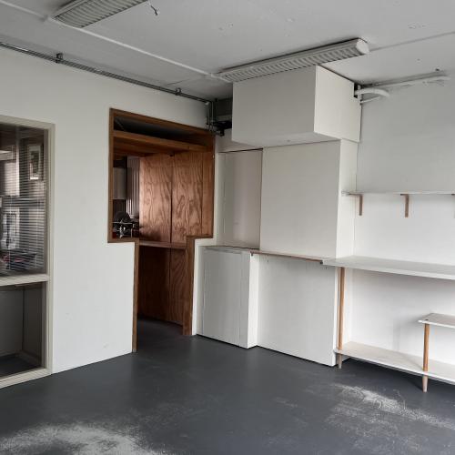 Modern interieur met witte ingebouwde kasten, een houten nis en open, minimalistische planken aan de muur.