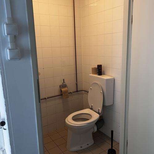 Interieur van een badkamer met een wc-toilet, rechthoekige tegels en een accessoirehouder.