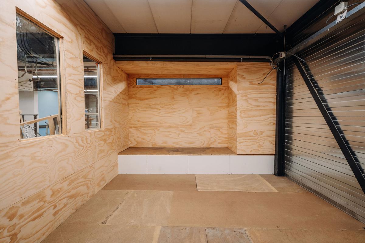 Onvoltooid interieur: houten wanden, ingebouwd nissen en zichtbare leidingen van een badkameropbouw.