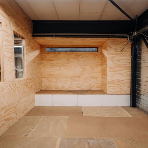 Onvoltooid interieur: houten wanden, ingebouwd nissen en zichtbare leidingen van een badkameropbouw.
