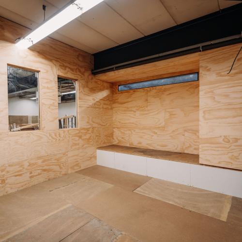 Interieur met licht hout en zwarte accenten, inclusief een ingebouwde bank en twee rechthoekige spiegels.