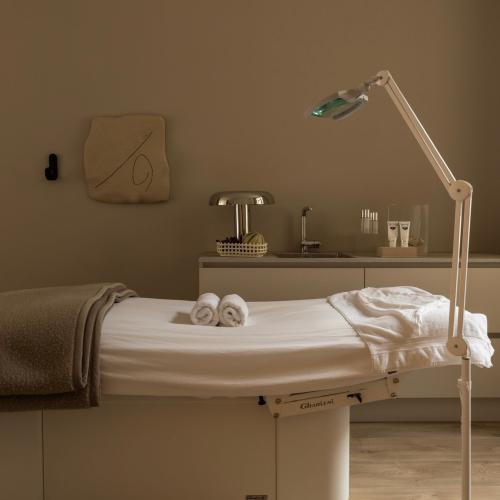 Wellnesskamer met een massagebed, make-up- en wastafel en een leeslamp.