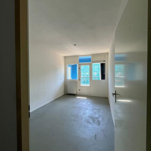 Leeg, modern binnenruimte met grijs betonvloer en badkamer/wc aan de rechterkant.