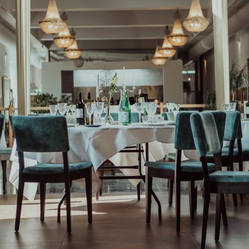 Een lange tafel voor een uitvaart of banket, gedekt met wit linnen, met veel flessen en kaarsen.