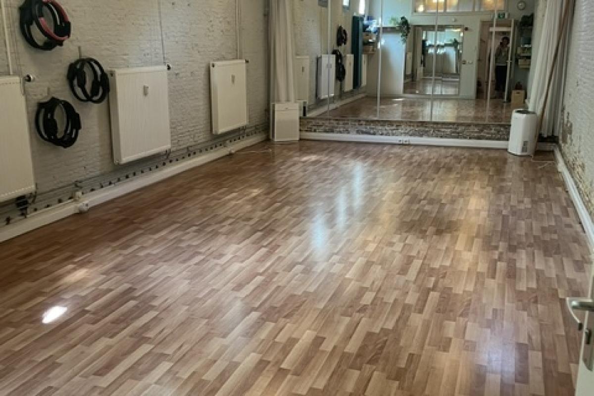 Een ruime, lege hal met glanzend houten laminaatvloer die diep naar het binnenste van de kamer leidt.