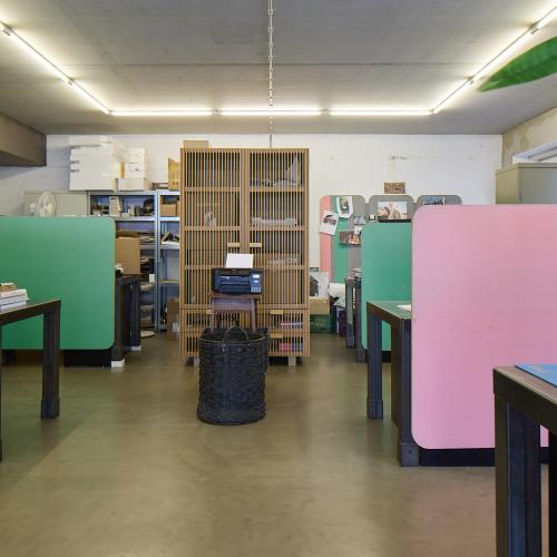 Interieurfoto van een rustig, modern bibliotheek- of kantoorruimte met veel groene en pastelkleurige elementen.