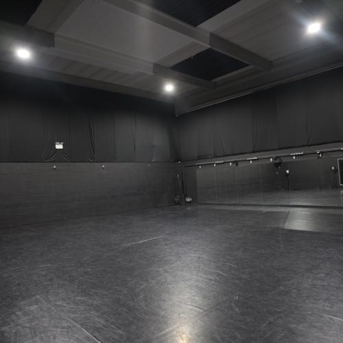 Groot, zwart, leeg en professioneel opgemaakt evenementen- of trainingsstudio met verlichting en een podium.