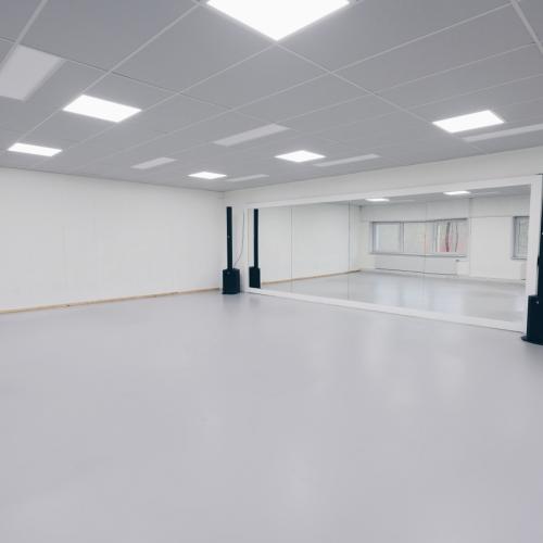 Groot, wit, leeg museum- of galerieruimte met meerdere spotlights en geluidsinstallaties.