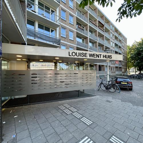 Louise Went Huis, ingang met metalen hek, fietsen, bomen, straat, daglicht.