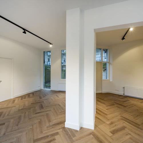 Luxe, lichte kamer met houten parket en moderne, lege architectuur.