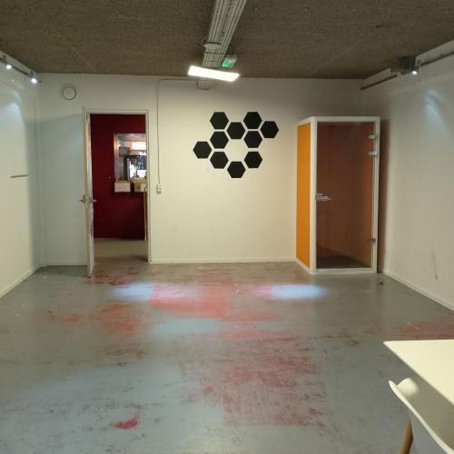 Lege galerie met witte muren en betonnen vloer. In het midden hangt een opstelling van zwarte cirkels.