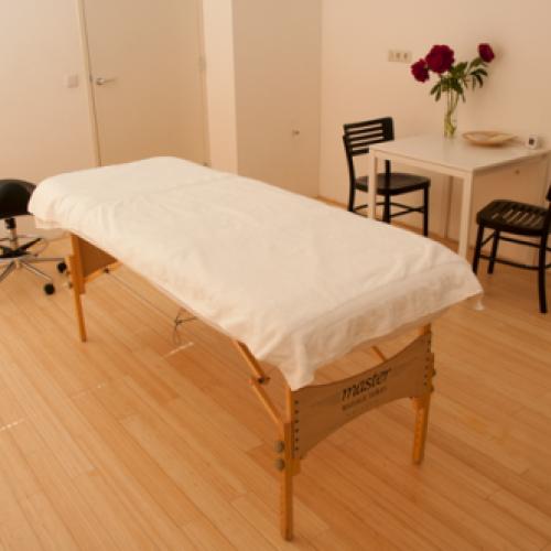 Kleine kamer met een bed, een bureau en enkele stoelen, ingericht in neutrale tinten.