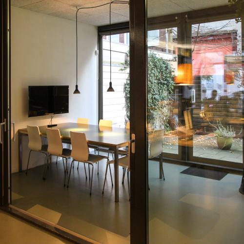 Interieur met een moderne eetruimte, gekenmerkt door een grote eettafel en slanke hanglampen, met uitzicht op een binnentuin.