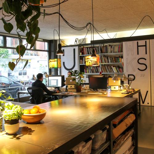 Modern interieur van een winkel met een grote, glanzende balie en boekenplanken, met daglicht en planten.