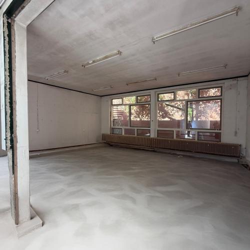 Leeg, modern interieur met hoge plafonds en een brede raammuur, klaar voor inrichting.