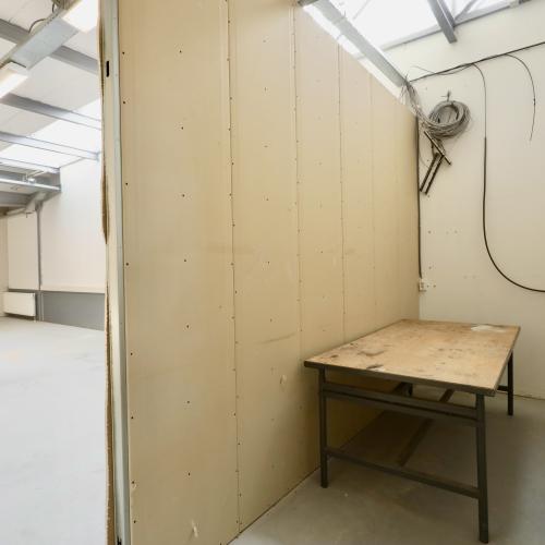 Interieur van een leeg pand met crèmekleurige, panelen wanden en een houten werktafel.