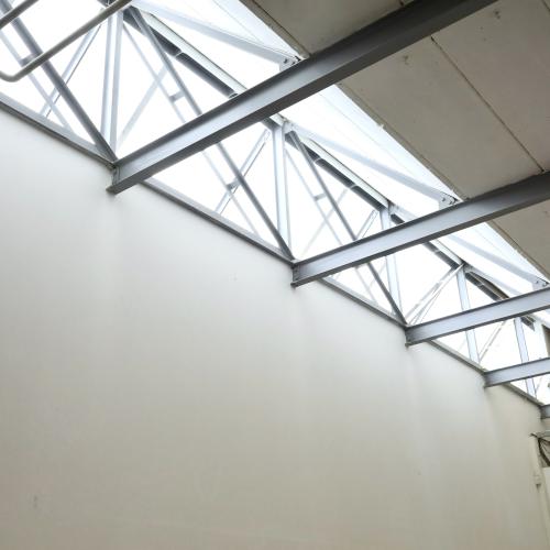 Modern dakraam met stalen kozijnen dat veel natuurlijk licht binnenlaat in een witte hal.