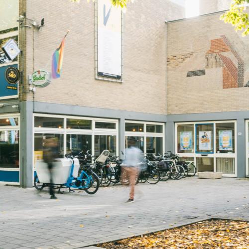 Straatgezichten met winkels, fietsen en voetgangers op de voorgrond.