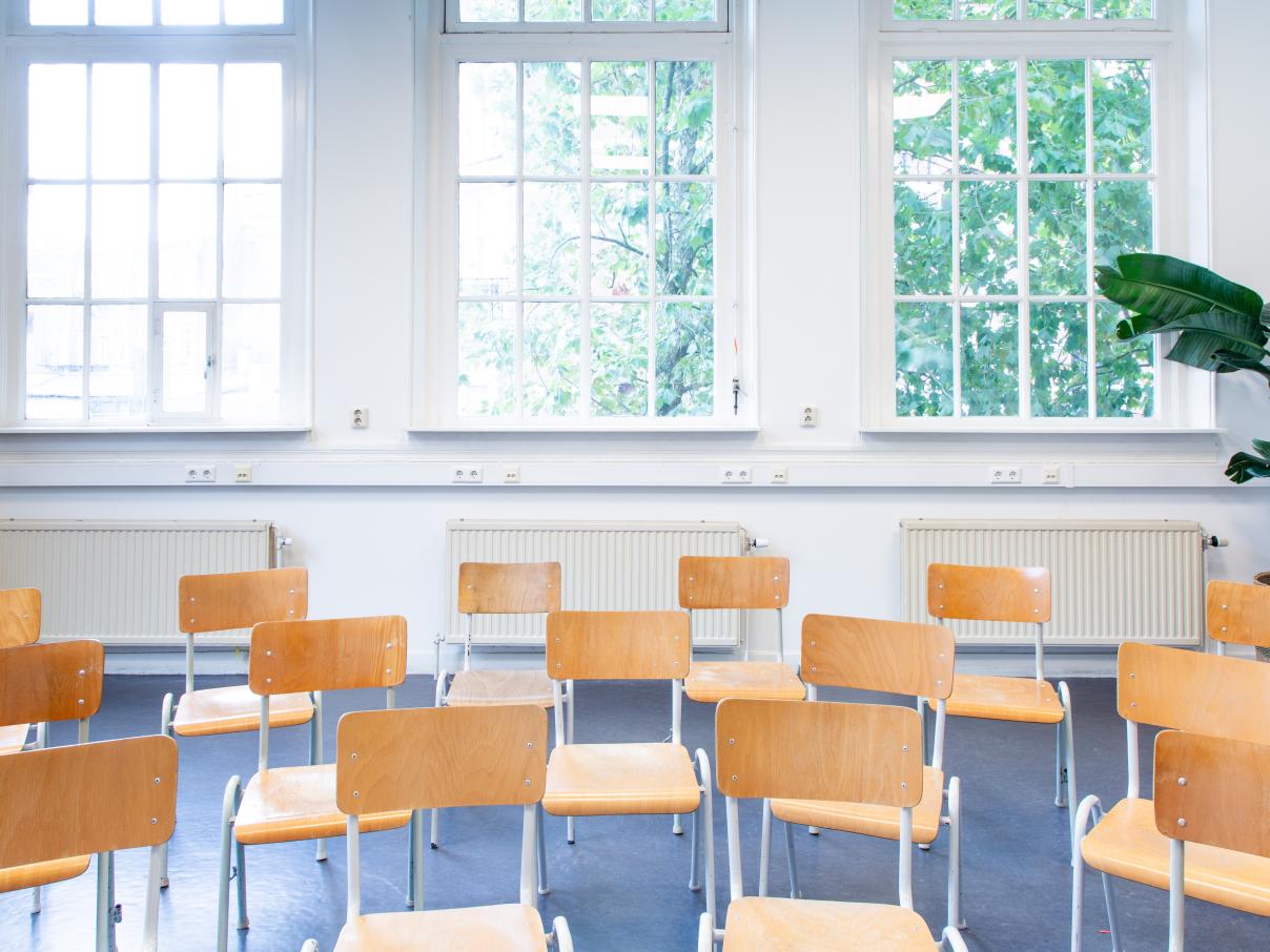 Stoelen in bioscoopopstelling met ramen op de achtergrond. Gezien van voren.