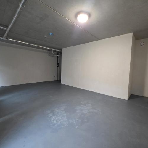 Leeg, grijs en rauw interieur met hoge plafonds, kale muren en zichtbare leidingen.