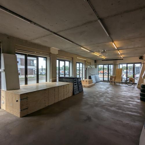 Grote, ruwe binnenruimte met hoog plafond, een lange lichte keukenbar en veel ramen voor natuurlijk licht.