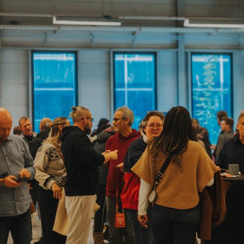 Groep mensen staand in een zakelijke evenementenruimte voor grote ramen.