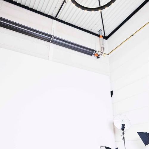 Industriële binnenruimte met een verhoogde houten vloer en een grote, donkere cirkelvormige ring die hangt.