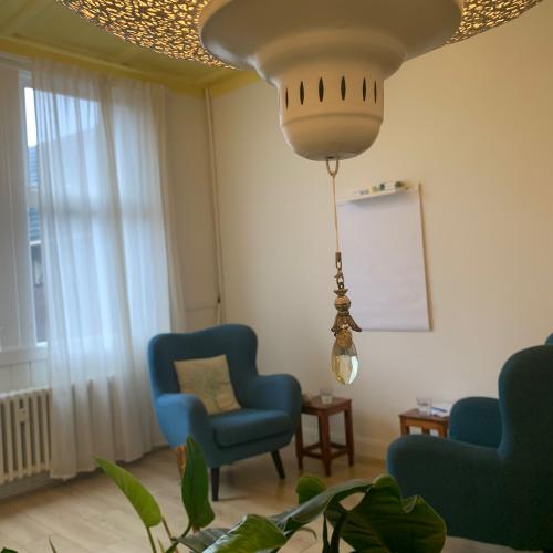 Zithoek met blauwe fauteuils, een grote hanglamp en een glinsterend, decoratief plafond.