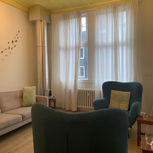 Interieurfoto van een zonnige woonkamer met bank, twee fauteuils, grote ramen en een opvallend geel plafond.