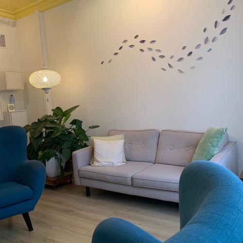 Moderne woonkamer met blauwe en lichte meubels. De muur is versierd met een sierlijk patroon van zwarte, vliegende vogels.